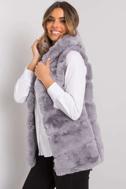 Woman wearing a gray faux fur sleeveless vest over a white blouse, showcasing a stylish and cozy winter fashion look.