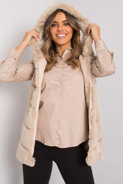 Woman wearing a beige hooded quilted gilet over a button-up shirt, displaying soft structure and casual elegance.