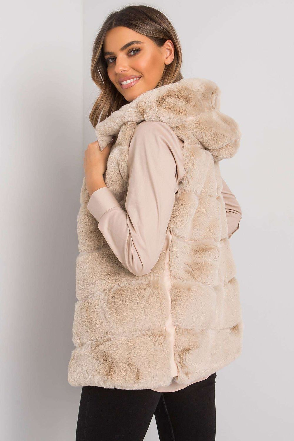 Woman wearing a plush, hooded, quilted gilet vest in beige, casually styled for layering, highlighting cozy and stylish outerwear.