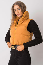 Woman wearing an orange puffer vest over a black sweater, showcasing a casual fall fashion look.