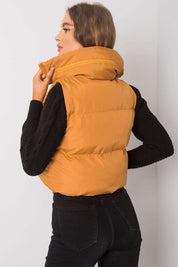 Back view of a woman wearing a khaki zip vest with a concealed hood, paired with black sleeves, showcasing a casual style.