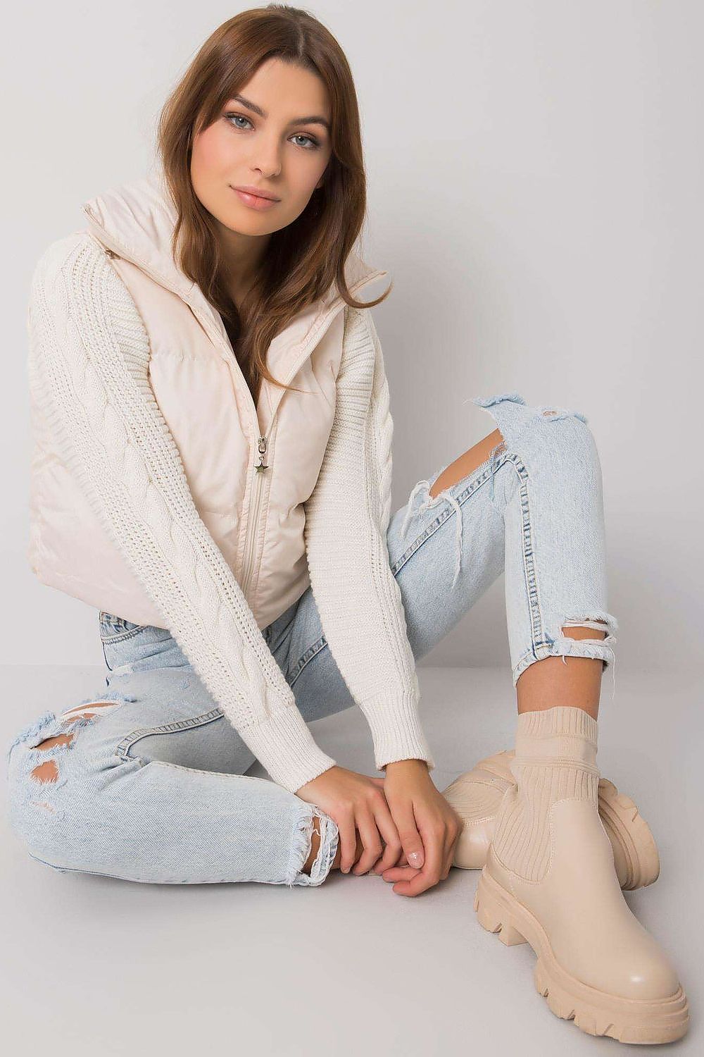 Woman wearing a white knit sweater with ripped jeans and beige boots