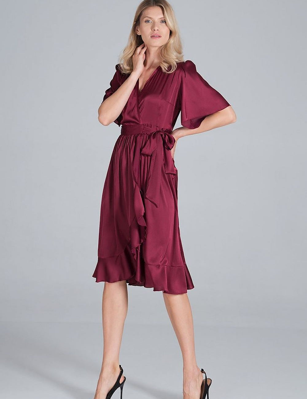 Graceful woman wearing Navira Satin Midi Wrap Dress with wide sleeves, waist tie, and flared hem, perfect for elegant gatherings.
