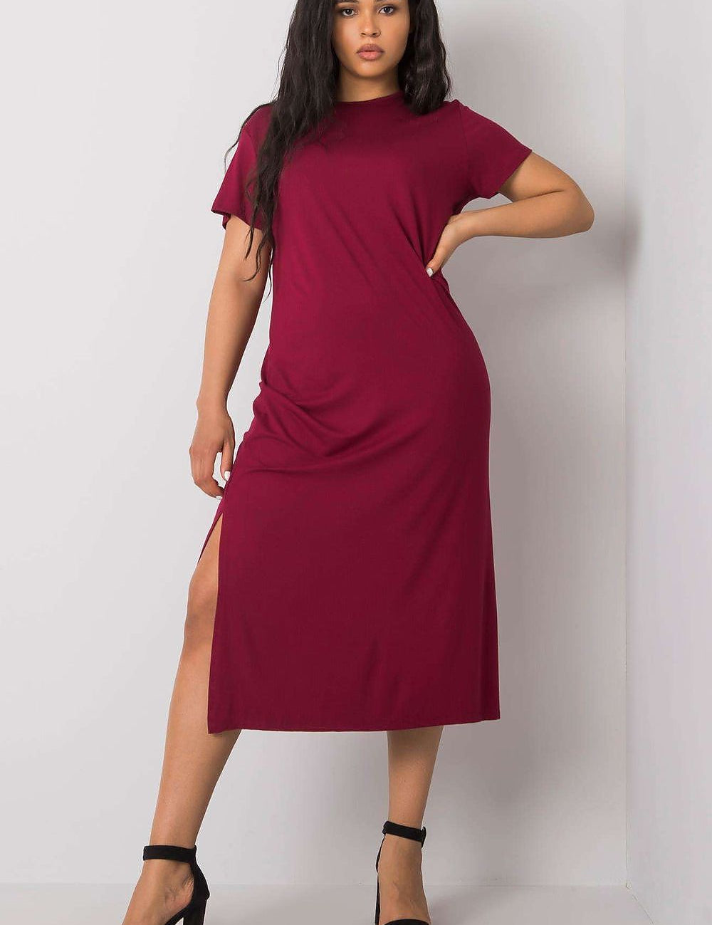 Woman wearing a plus size Serelinne casual summer dress in red, featuring short sleeves and side slit, paired with black heels.