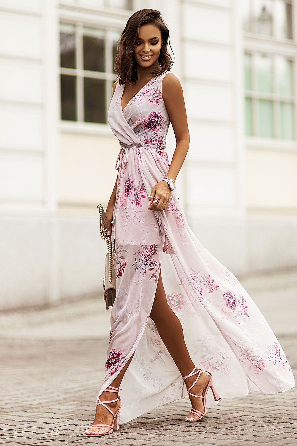 Woman wearing a floral plus size chiffon maxi dress with V-neckline and side slit, showcasing elegant summer fashion on a city street.