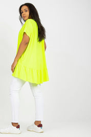 Woman wearing Plus Size Alveria Frilled Tunic in bright yellow with short sleeves and flowing asymmetrical hem, paired with white pants.