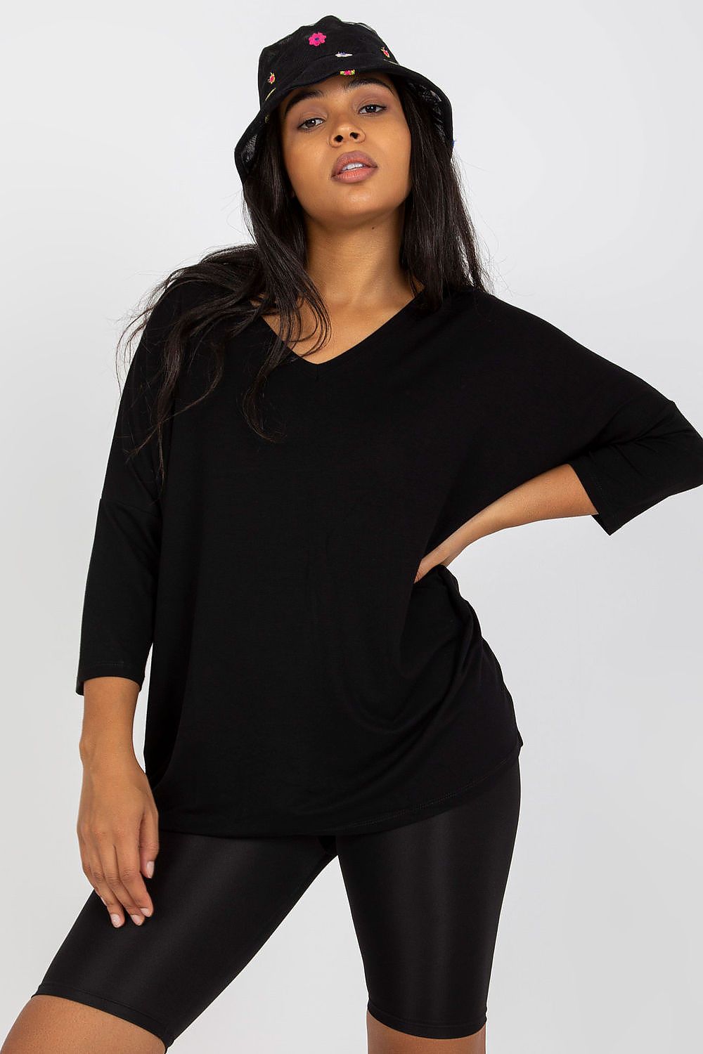 Woman wearing black 3/4 sleeve blouse with sweetheart neckline and black shorts, posing confidently with hand on hip.