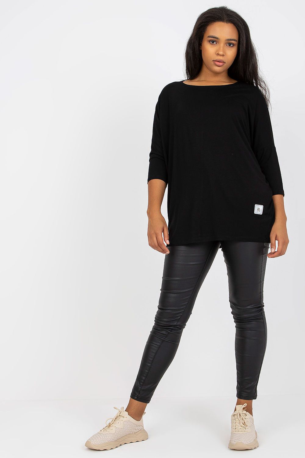 Model wearing Plus Size Bellarie Cotton Blouse in black with 3/4 sleeves, paired with black leggings and beige sneakers.