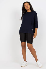 Model wearing a navy blue Plus Size Bellarie Cotton Blouse with 3/4 sleeves and boat neckline, paired with black shorts and white sneakers.