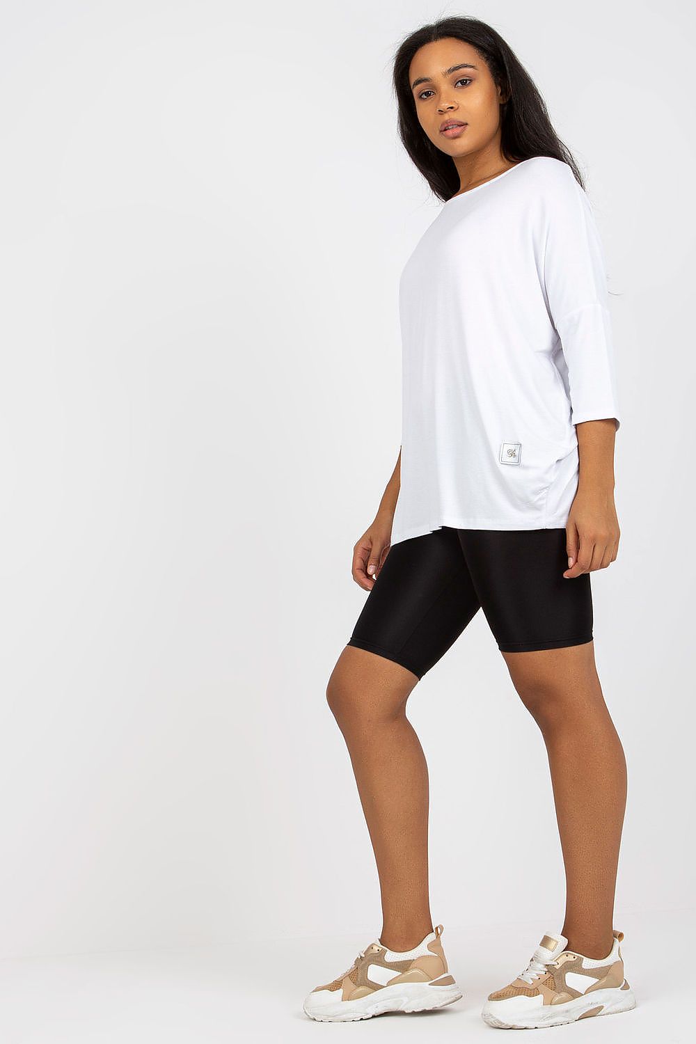 Woman wearing Plus Size Bellarie Cotton Blouse with 3/4 sleeves, styled with black shorts and sneakers.