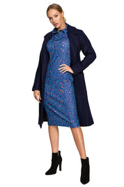 Model wearing Alvenora Belted Fleece Long Coat over blue patterned dress, highlighting classic collar and waist-tie belt.