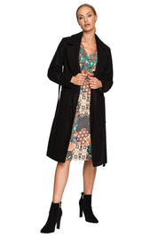 Woman wearing Alvenora Belted Fleece Long Coat with classic collar, patch pockets, and waist tie, styled over a colorful patterned dress.