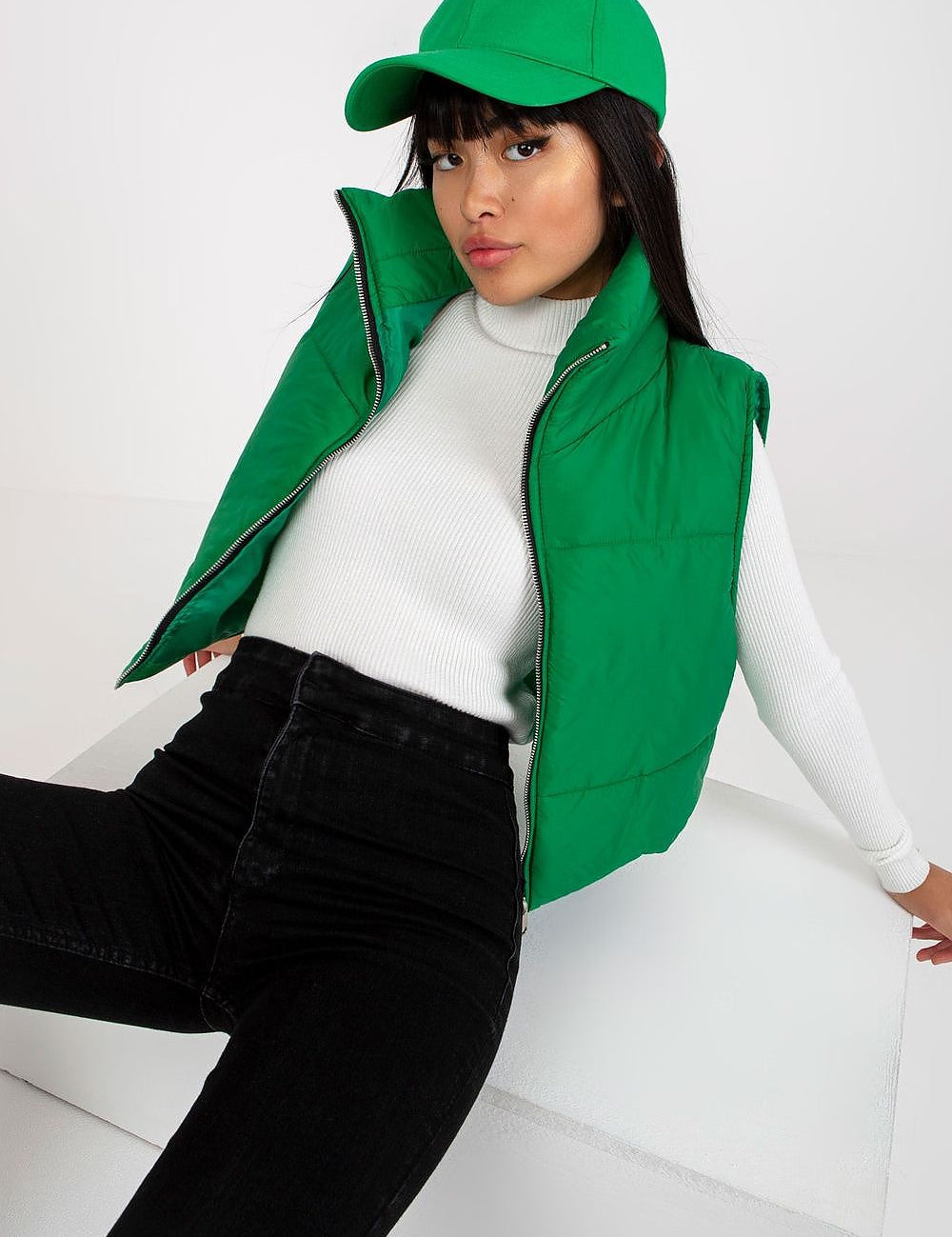 Model wearing green Irdena Insulated Quilted Gilet Vest, styled with a white top and matching green cap, showcasing modern casual fashion.