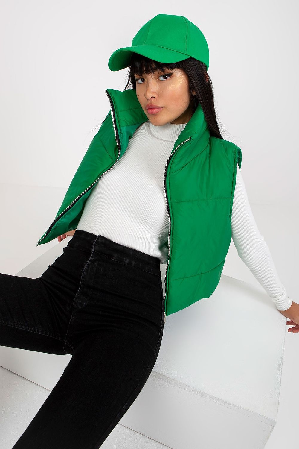 Model wearing green Irdena Insulated Quilted Gilet Vest, styled with a white top and matching green cap, showcasing modern casual fashion.
