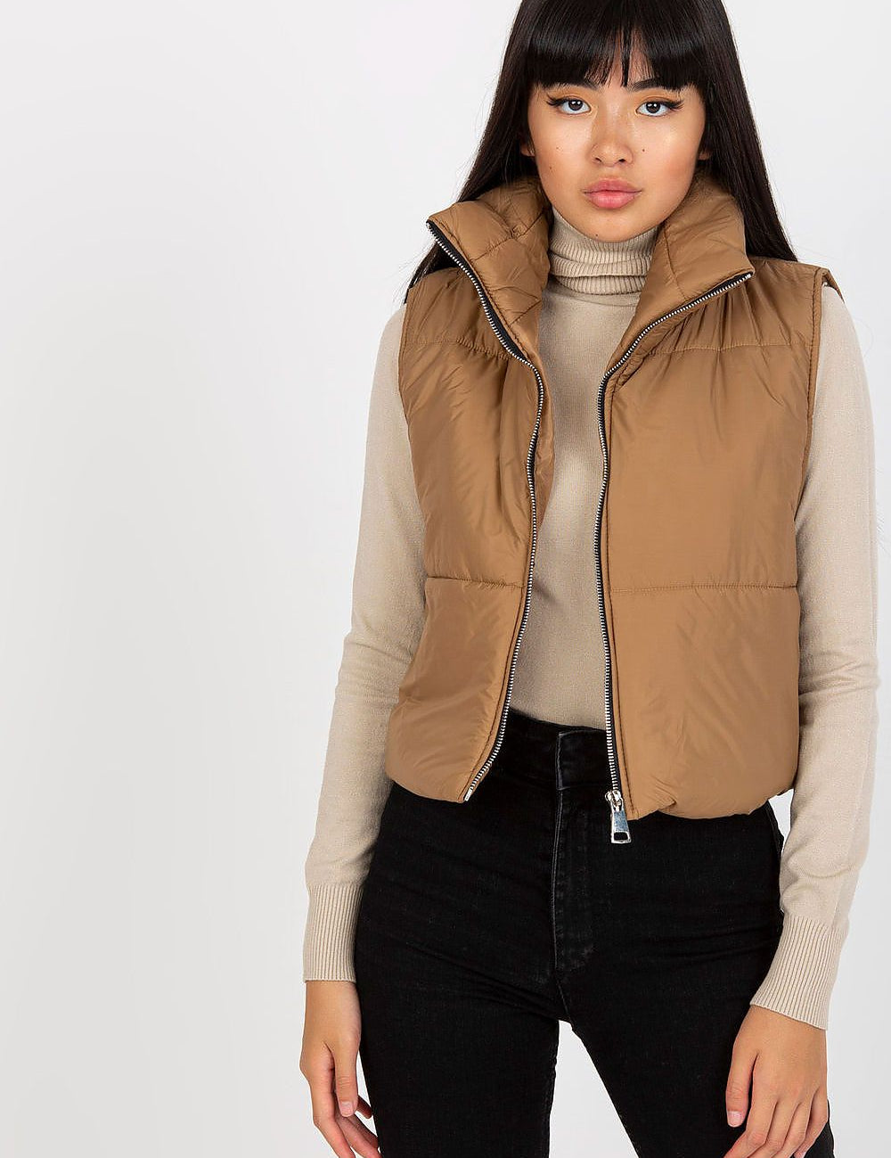 Model wearing Irdena Insulated Quilted Gilet Vest, short and cozy with zippered front, styled over a beige sweater for casual city look.