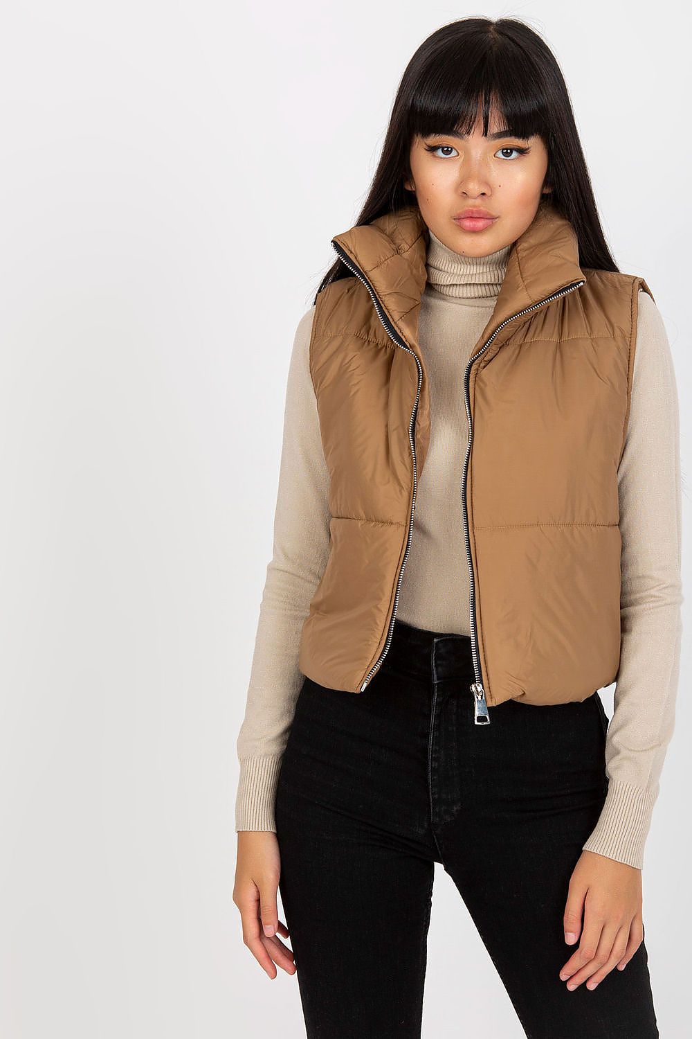 Model wearing Irdena Insulated Quilted Gilet Vest, short and cozy with zippered front, styled over a beige sweater for casual city look.