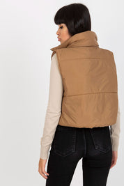 Back view of a woman wearing a brown Irdena insulated quilted gilet vest, showcasing the cropped and stylish design for transitional layering.