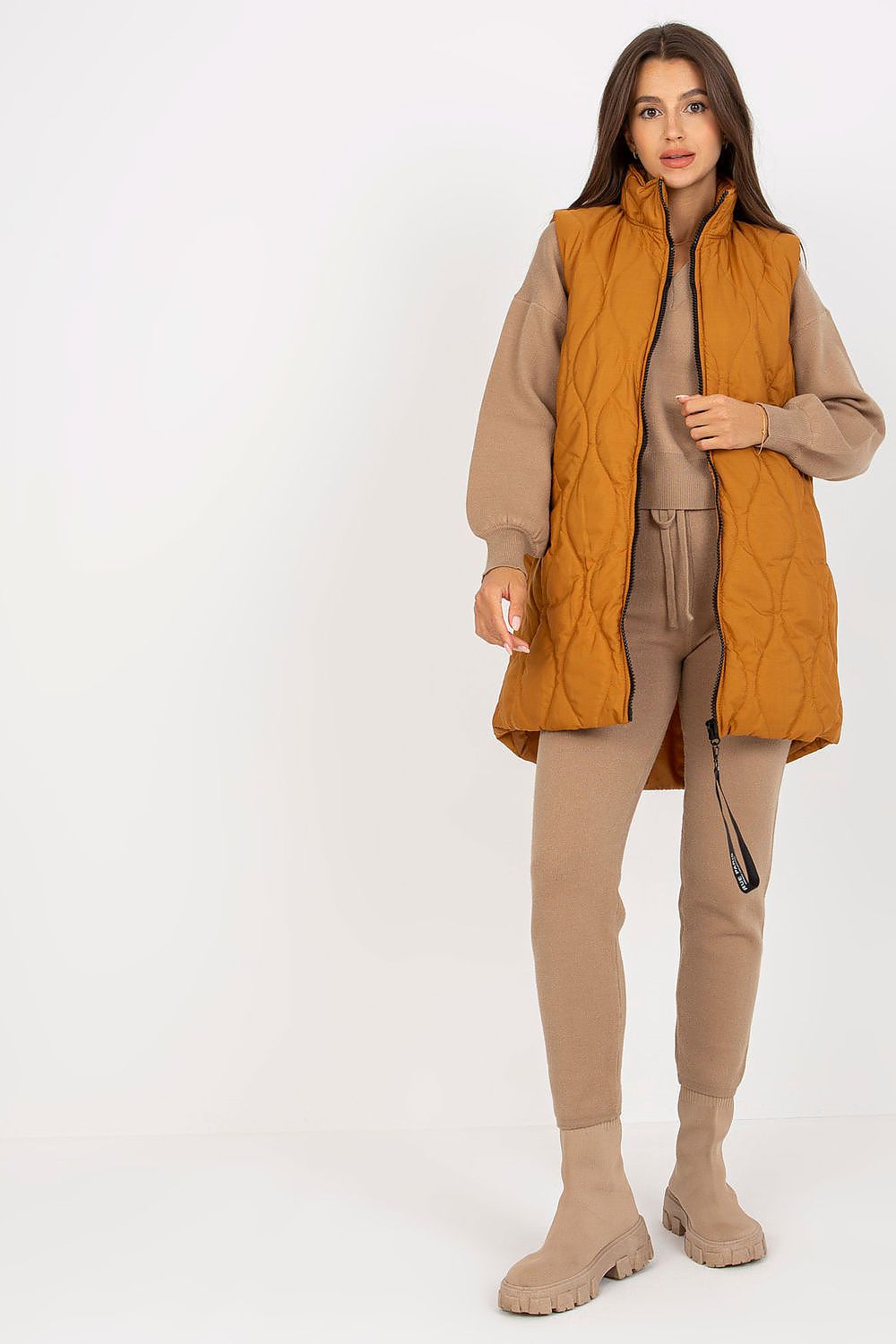 Woman wearing Syverelle quilted gilet vest with sleek zipper, minimalist style in mustard color, perfect for layered outfits.