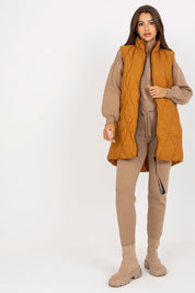 Woman wearing Syverelle quilted gilet vest with sleek zipper, minimalist style in mustard color, perfect for layered outfits.