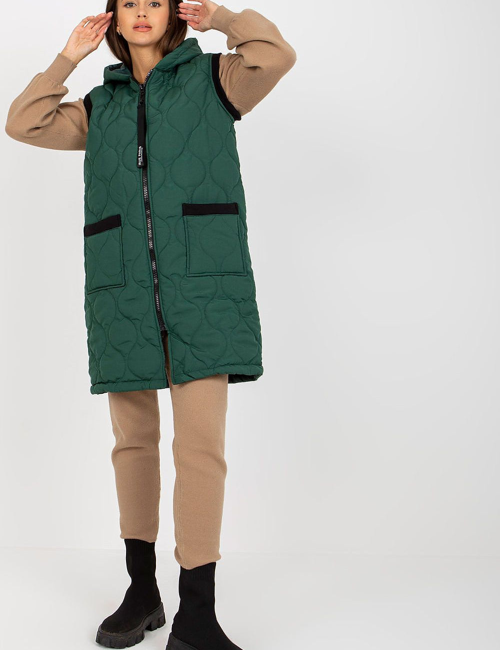 Model wearing Virethia Quilted Hooded Gilet in green, showcasing a casual layered outfit with front sewn-on pockets for transitional weather.