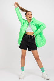 Woman wearing a green Serentha quilted jacket with hood, paired with shorts and sneakers, showcasing casual trendy style.