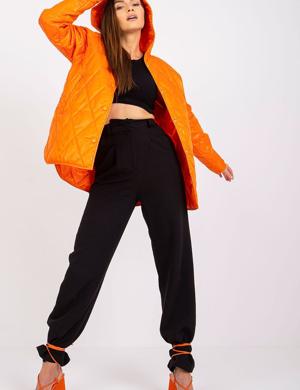 Model wearing Serentha Hooded Quilted Jacket in orange, showcasing its cozy hood, sleek button detail, and chic silhouette for fall style.