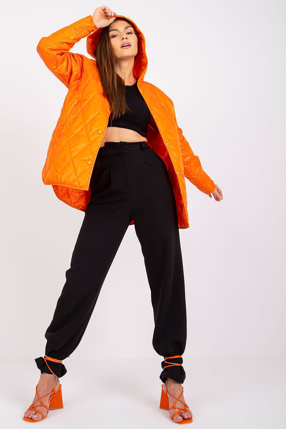 Model wearing Serentha Hooded Quilted Jacket in orange, showcasing its cozy hood, sleek button detail, and chic silhouette for fall style.