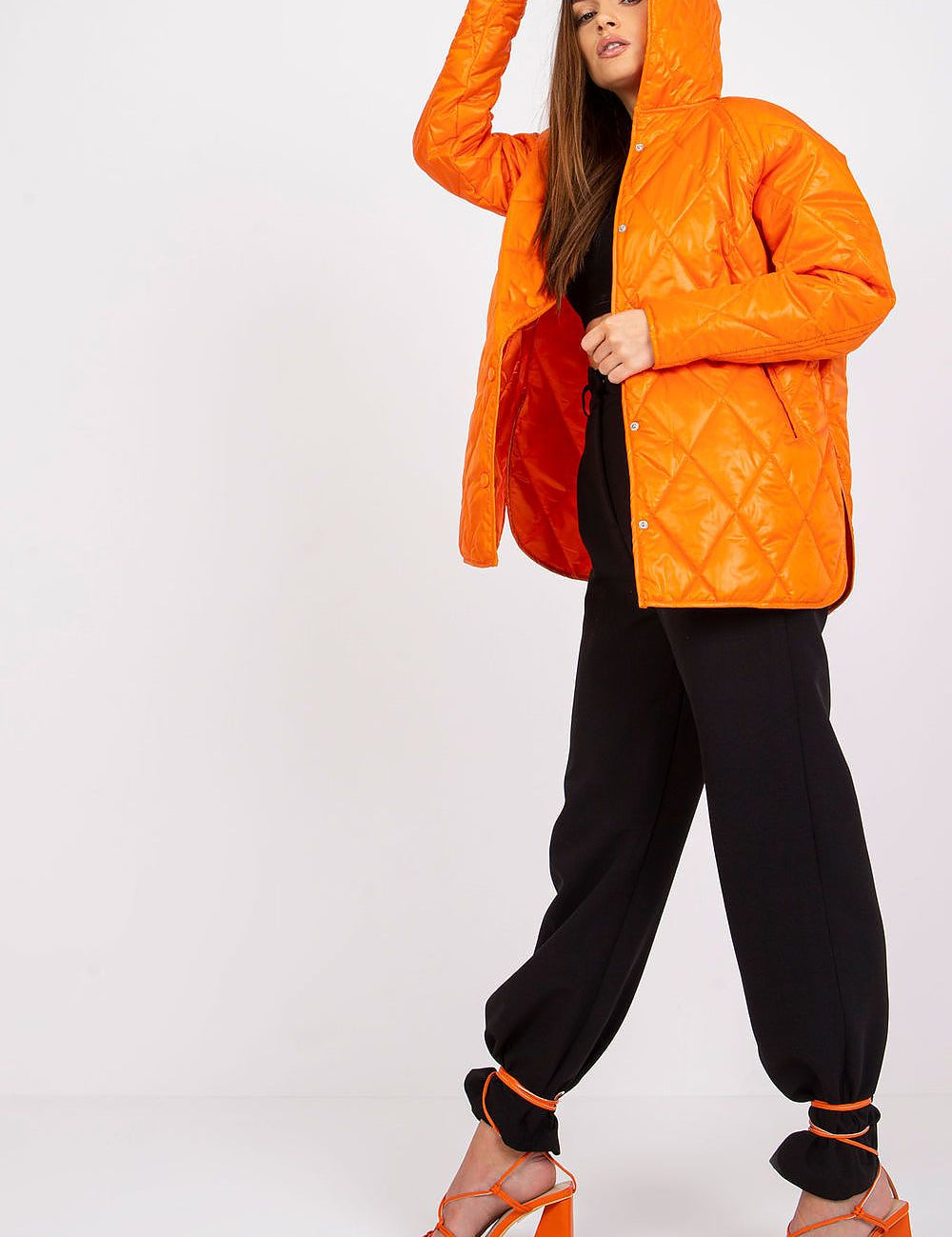 Woman wearing Serentha Hooded Quilted Jacket in orange, featuring a cozy hood and sleek design, perfect for transitional layering.