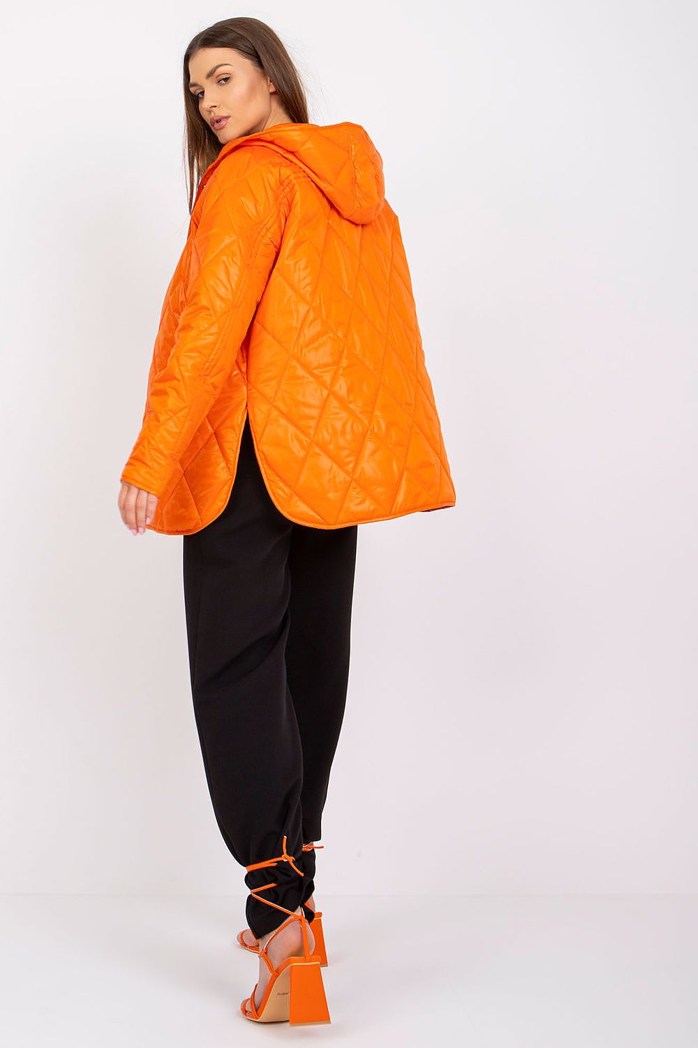 Woman wearing orange Serentha Hooded Quilted Jacket with sleek design, cozy hood, and elegant silhouette, ideal for transitional seasons.