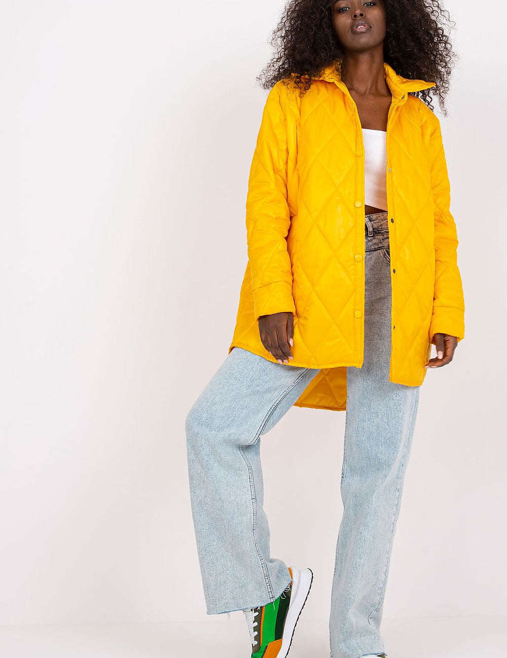 Woman wearing Cerenya Quilted Jacket with Extended Back in yellow, paired with jeans and sneakers, showcasing casual elegance.