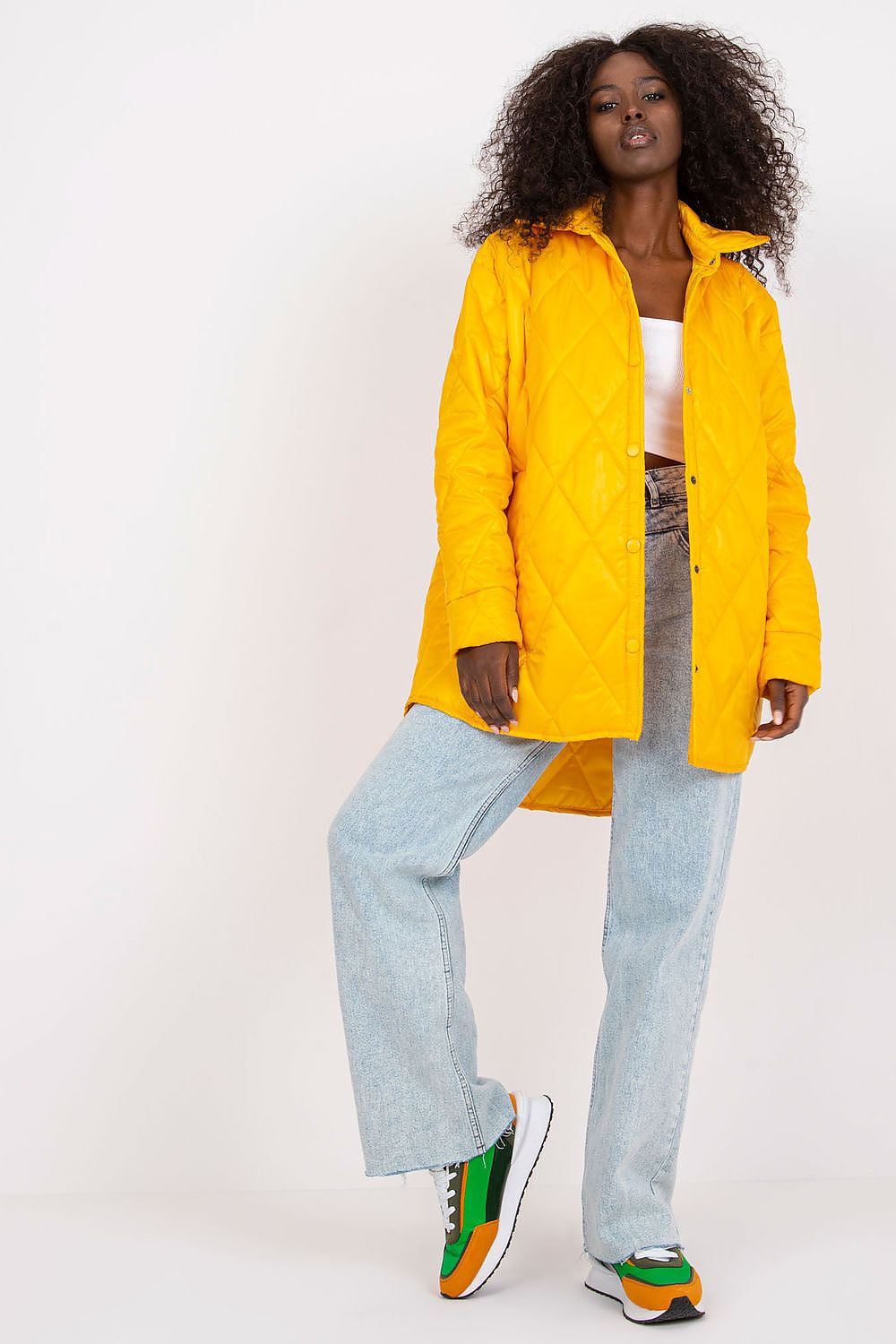 Woman wearing Cerenya Quilted Jacket with Extended Back in yellow, paired with jeans and sneakers, showcasing casual elegance.