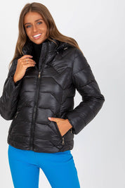 Woman wearing black Evelora Quilted Gilet with detachable hood, featuring long sleeves, zippered pockets, and sleek front zipper.