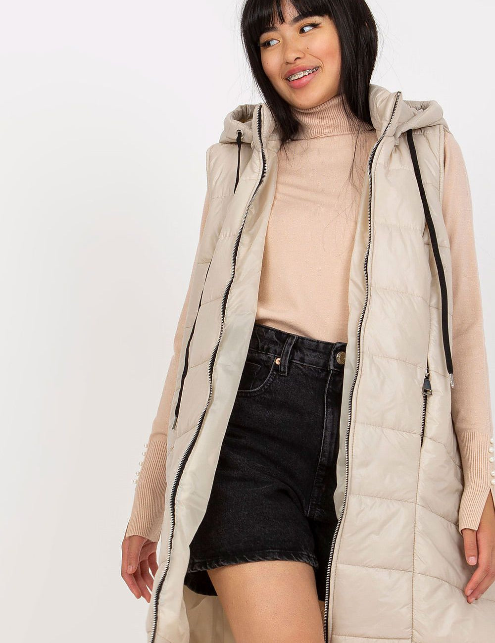 Woman wearing Evrendelle Quilted Longline Vest with detachable hood and front zipper for transitional weather.