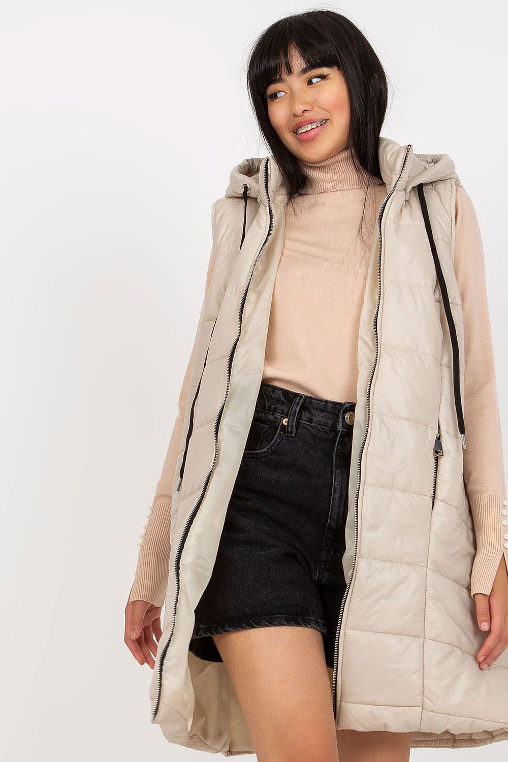 Woman wearing Evrendelle Quilted Longline Vest with detachable hood and front zipper for transitional weather.