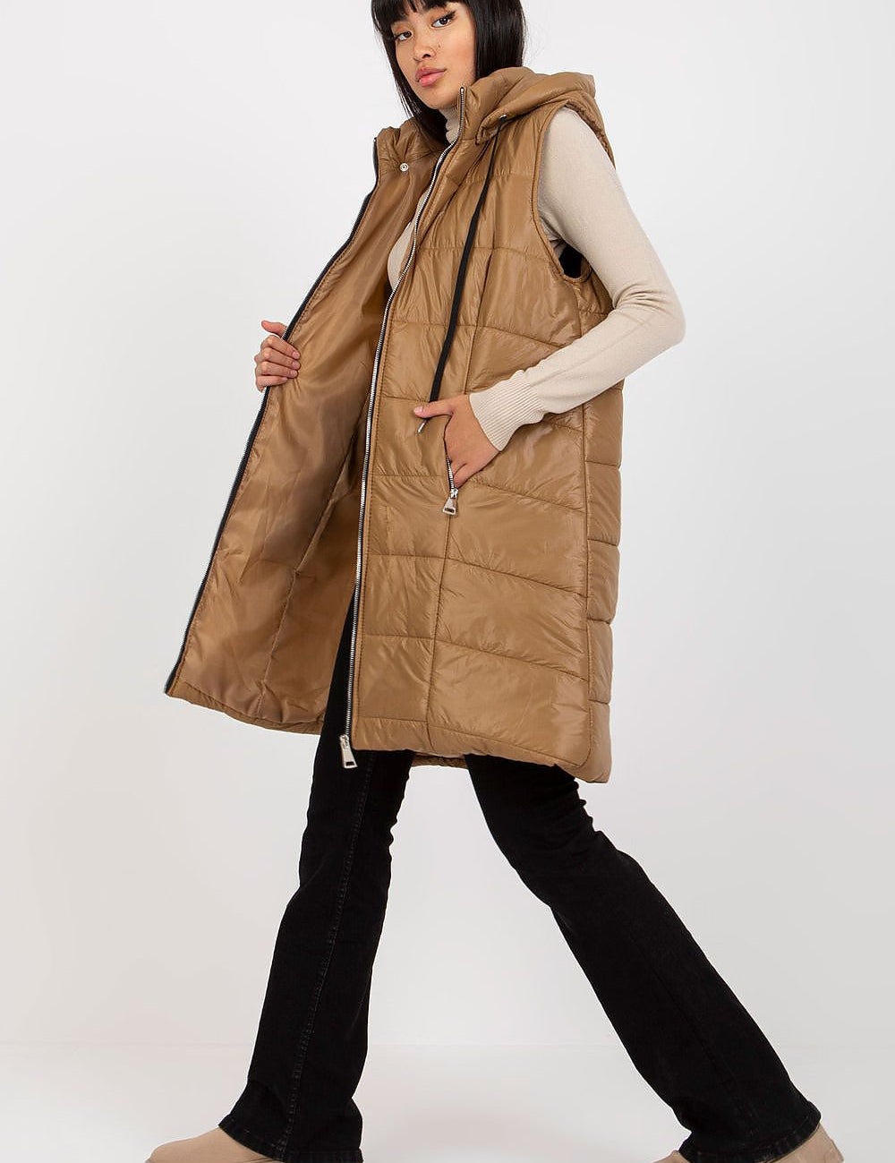Woman wearing brown Evrendelle quilted longline vest with detachable hood and front zipper, showcasing transitional season fashion.