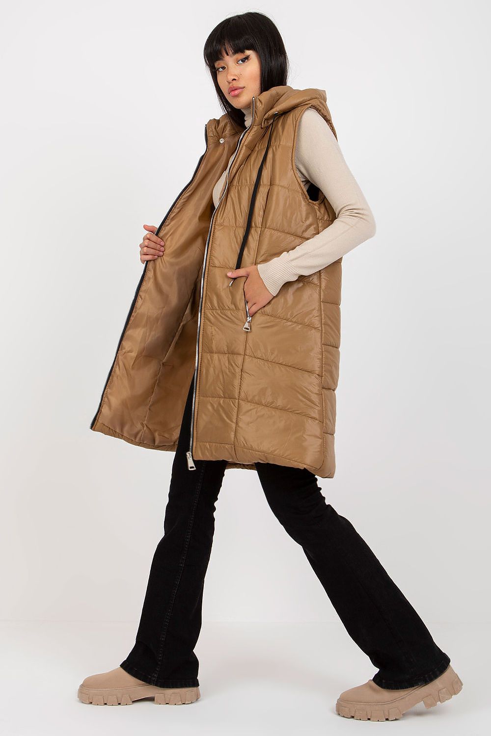 Woman wearing brown Evrendelle quilted longline vest with detachable hood and front zipper, showcasing transitional season fashion.