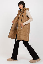 Woman wearing brown Evrendelle quilted longline vest with detachable hood and front zipper, showcasing transitional season fashion.