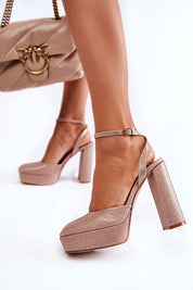 Woman wearing pink glitter platform heels with ankle strap and carrying a beige handbag.
