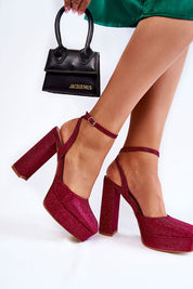 Woman wearing glittery red platform sandals with ankle strap, carrying a small black handbag, showcasing elegant evening footwear.