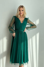 Woman wearing Marleia mesh-layered evening midi dress with sheer sleeves in a sunlit room.