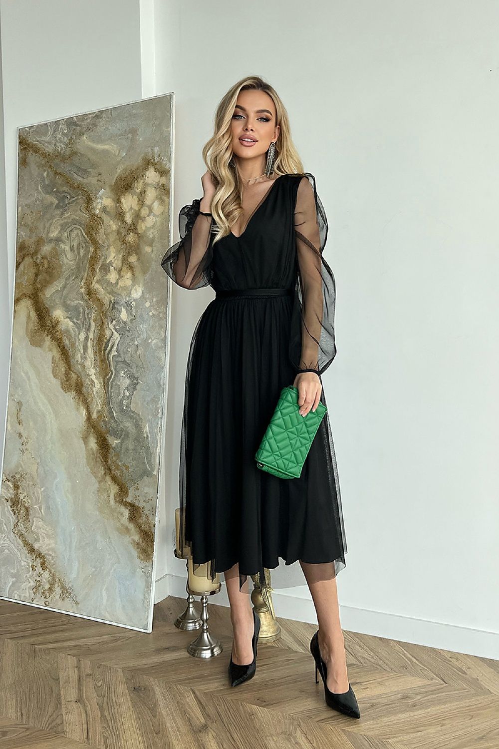 Woman wearing Marleia Mesh-Layered Evening Midi Dress with sheer sleeves, holding a green clutch in a stylish indoor setting.