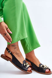 Woman wearing Dorellia Leather Flat Sandals with chain detail, showcasing green pants and tattoo, perfect for stylish summer looks.