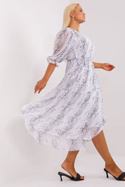 Woman modeling Plus Size Delmira Waist-Tie Midi Dress, featuring 3/4 sleeves, round neckline, and waist-tie, in a flowing white fabric.