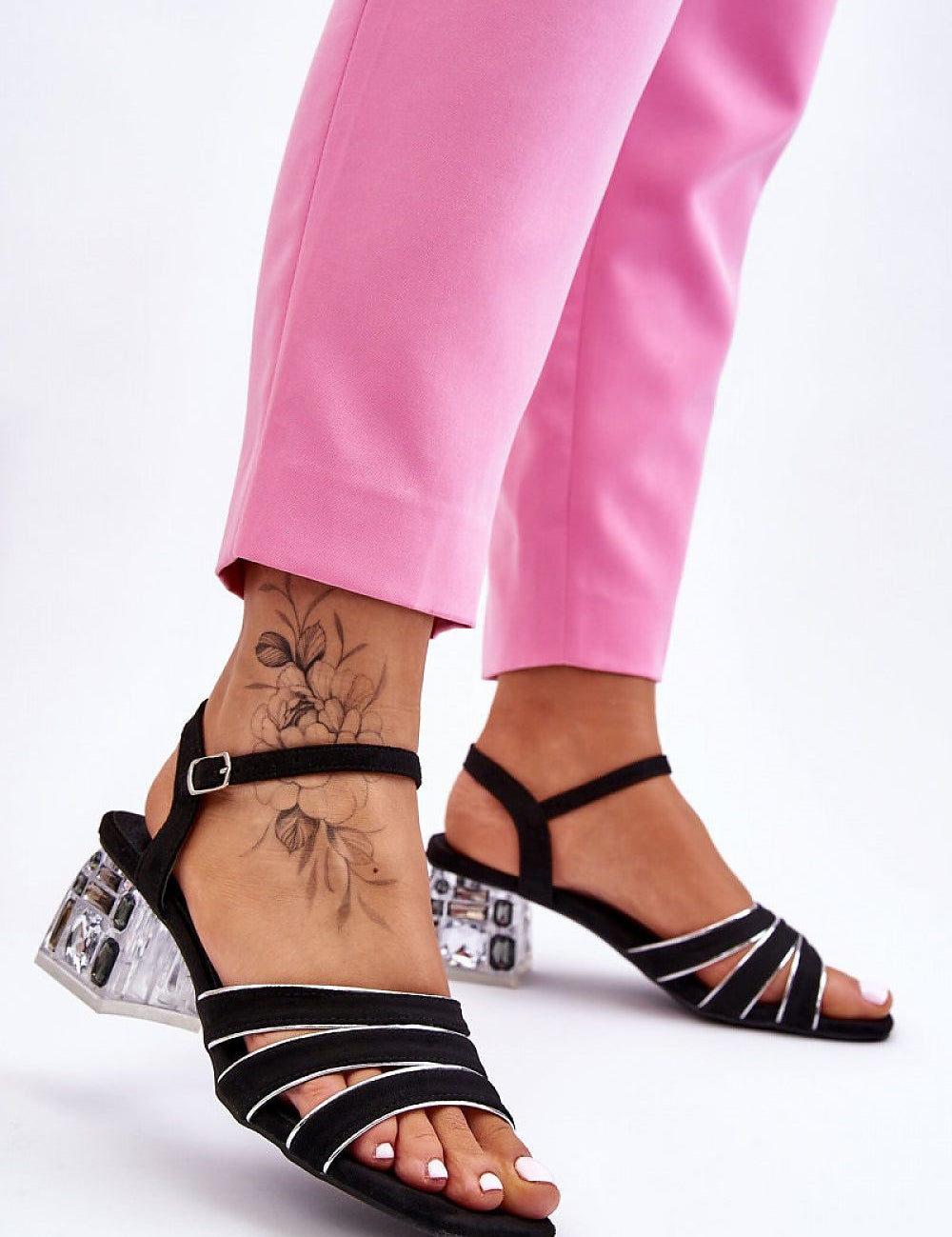 Woman wearing Arnevie suede block heel sandals with embellished heel and open square toe, paired with pink pants.