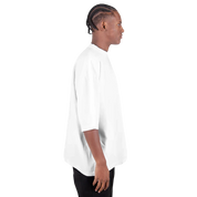 Side view of a man wearing a Shaka Wear oversized drop-shoulder crewneck t-shirt in white, showcasing its relaxed fit and streetwear style.