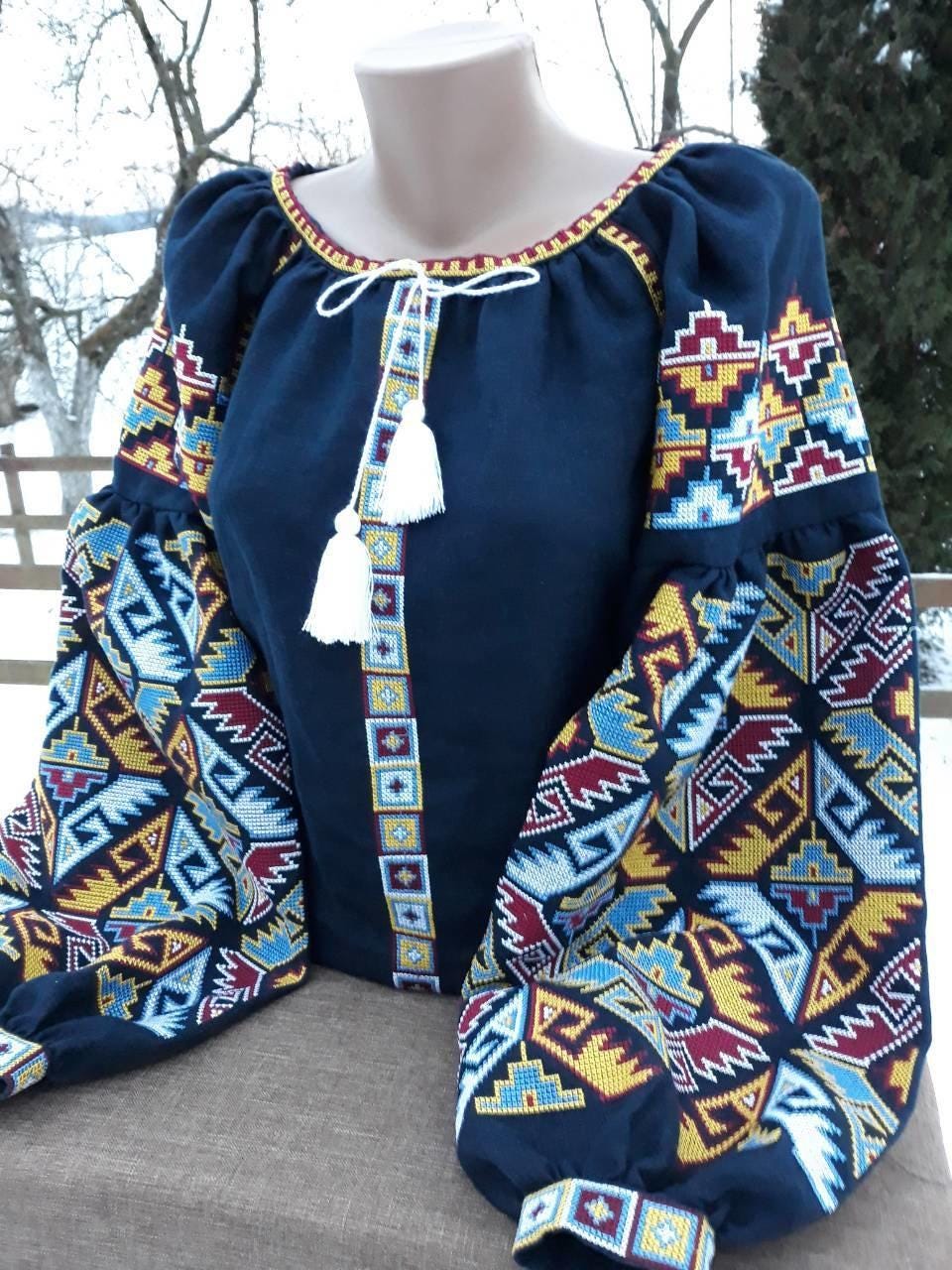 Traditional dark blue embroidered Ukrainian Vyshyvanka blouse with colorful folk motifs for women, shown outdoors.