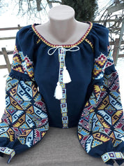 Dark blue Ukrainian embroidered blouse with folk motifs and silk thread cross-stitch, featuring long patterned sleeves.