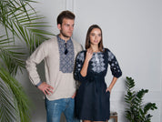 Man in embroidered beige shirt and woman in dark blue linen dress with Alatyr symbol, traditional Ukrainian vyshyvanka attire.