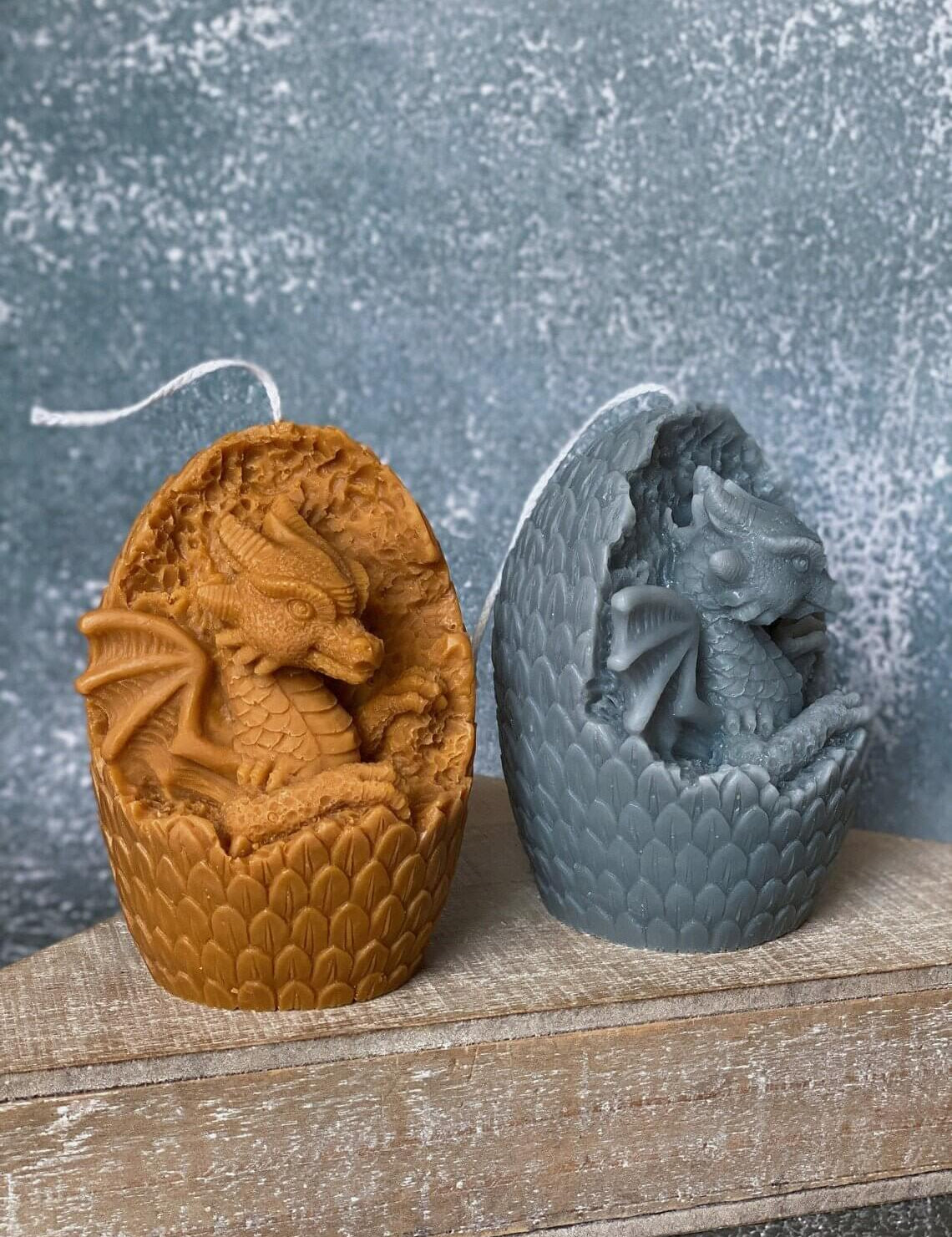 Handmade dragon's egg candles, crafted from natural soy wax in various colors, resting on wooden surface.