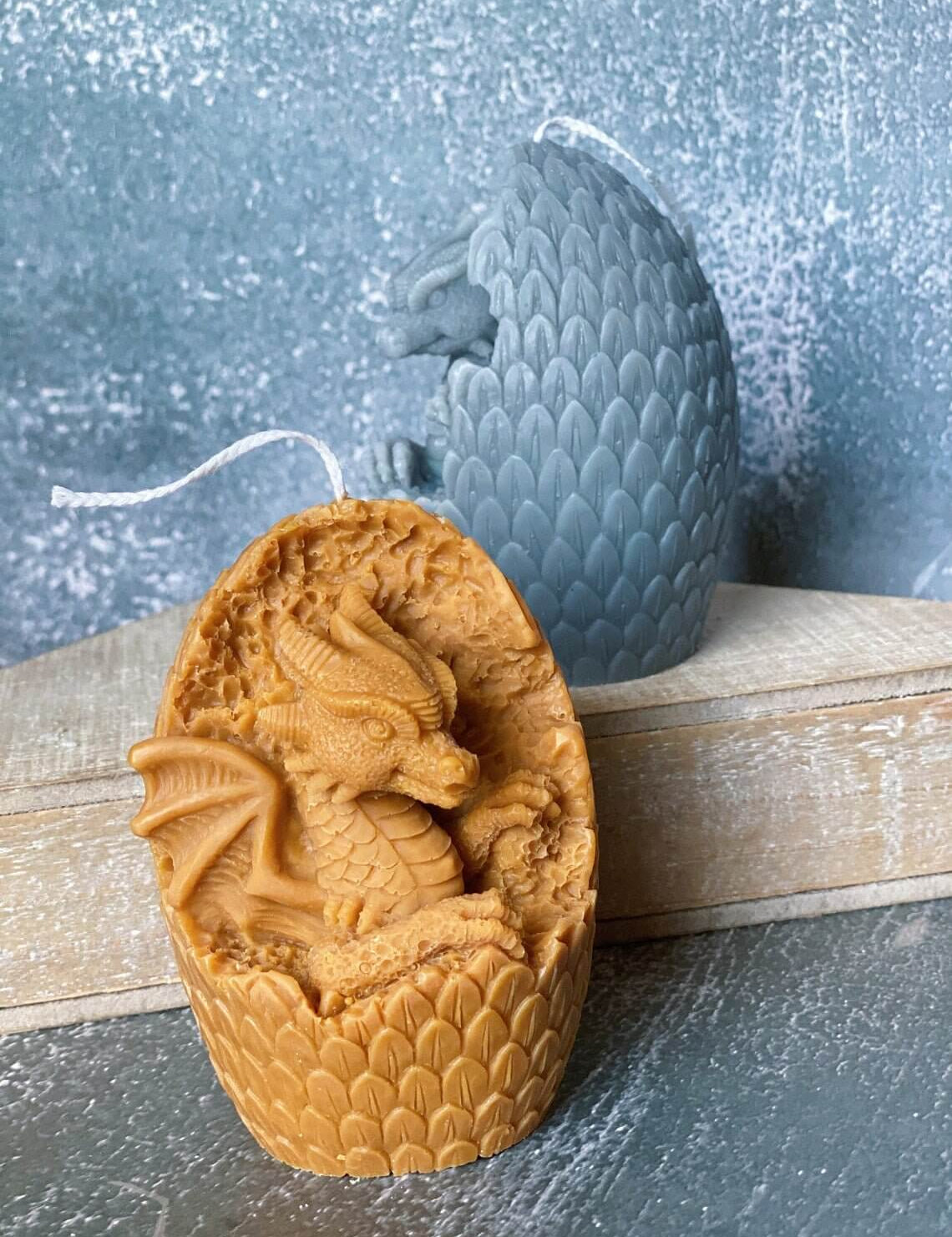 Handmade dragon egg candle with sculpted dragon, crafted from soy wax, displayed with textured background, combines mythical charm and warmth.